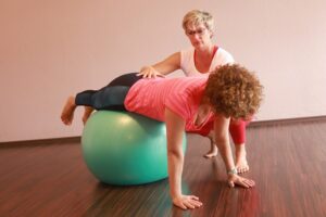 1fach Yoga | 1fach Gesund - Team - Silke Wagner bei therapeutischer Einzelstunde mit Patientin auf dem Ball