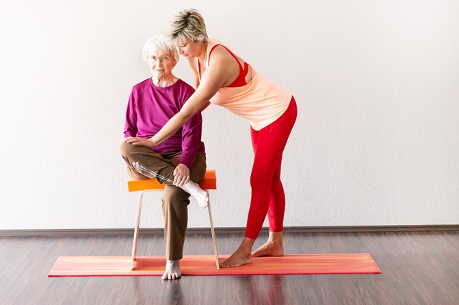 1fach Yoga | 1fach Gesund - Kurs Yoga auf dem Stuhl - Silke Wagner in Übung mit Yogaschülerin auf dem Stuhl
